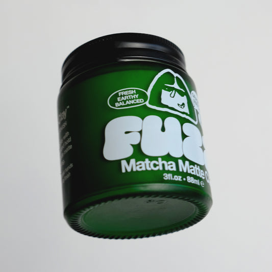 Green container of FUZZ Matcha Matte Clay on a gray background